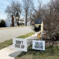 A yard sign saying "Don't Give Up" planted in the grass.