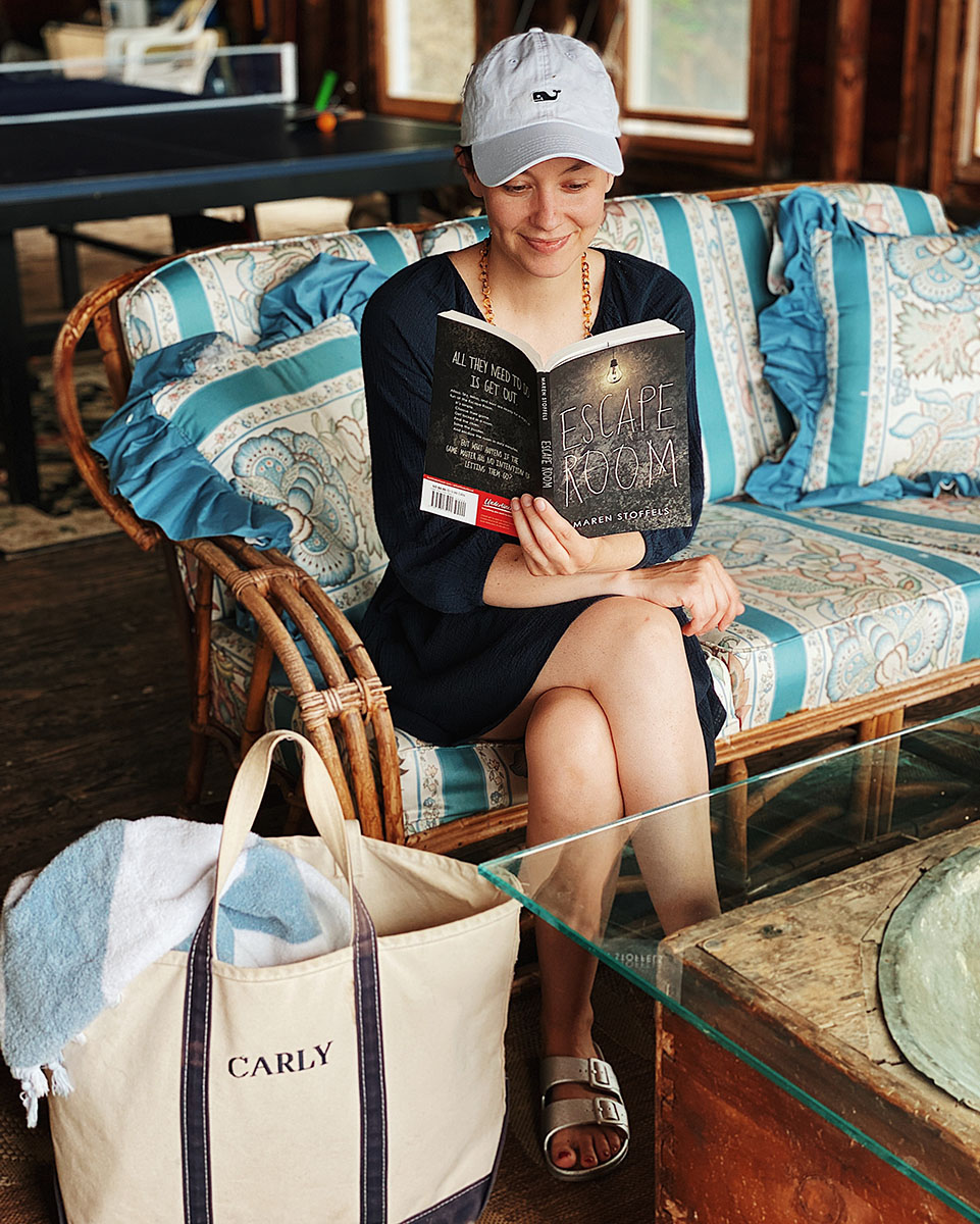 Carly sitting in a boathouse while reading Escape Room