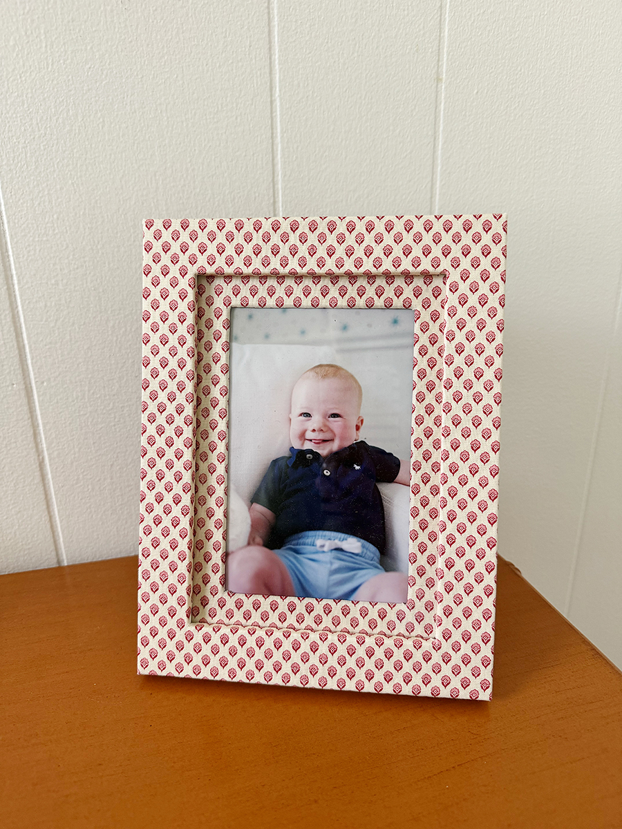 A photo of Carly's son Rory in a red and white fabric wrapped picture frame on her desk.