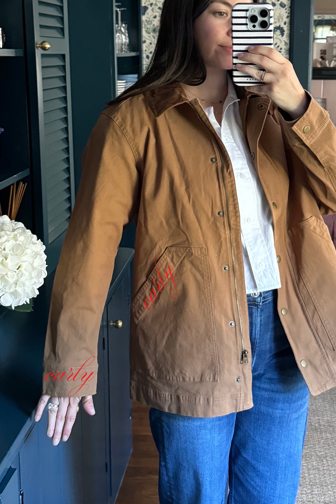 Carly wearing a barn jacket with a mockup of monograms on the sleeve and pocket