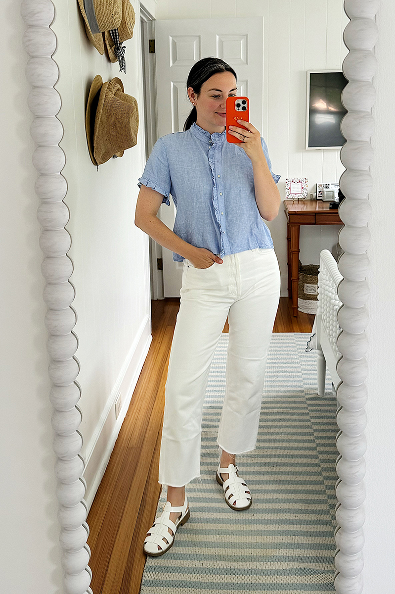 A mirror selfie of Carly wearing white jeans and a blue ruffle linen shirt from J. Crew. 