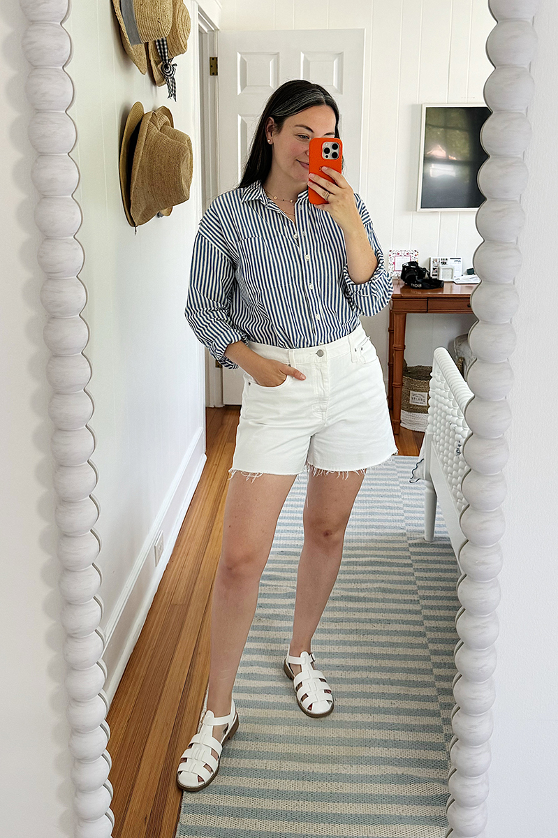 A mirror selfie of Carly wearing white jean shorts and a striped blue shirt.