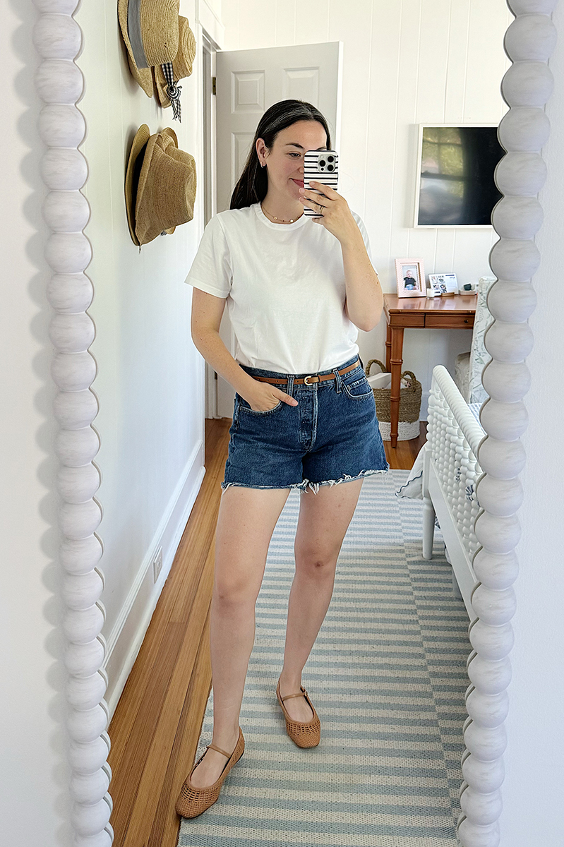 A mirror selfie of Carly wearing a denim shorts and a white tee and mary janes.