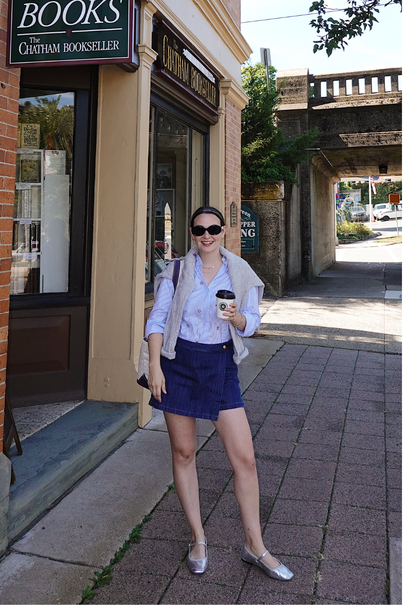 Carly Riordan wearing an embellished shirt, denim skort, and metallic mary janes.