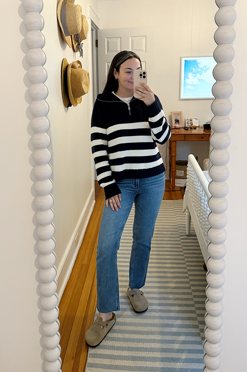 Carly Riordan taking a mirror selfie wearing a stripe pullover with jeans. 