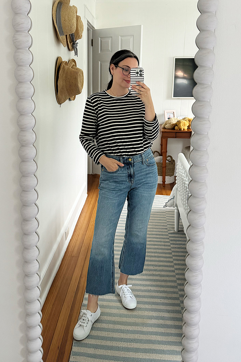 A mirror selfie of Carly wearing jeans and a navy and white striped shirt.