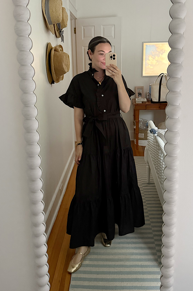 Carly Riordan taking a mirror selfie wearing a black maxi dress.