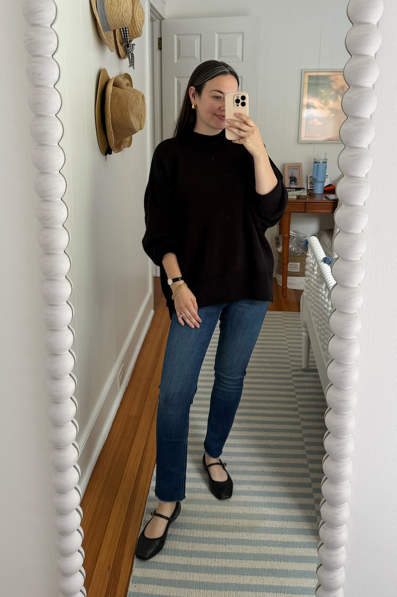 Carly Riordan taking a mirror selfie wearing an oversized tunic and jeans.