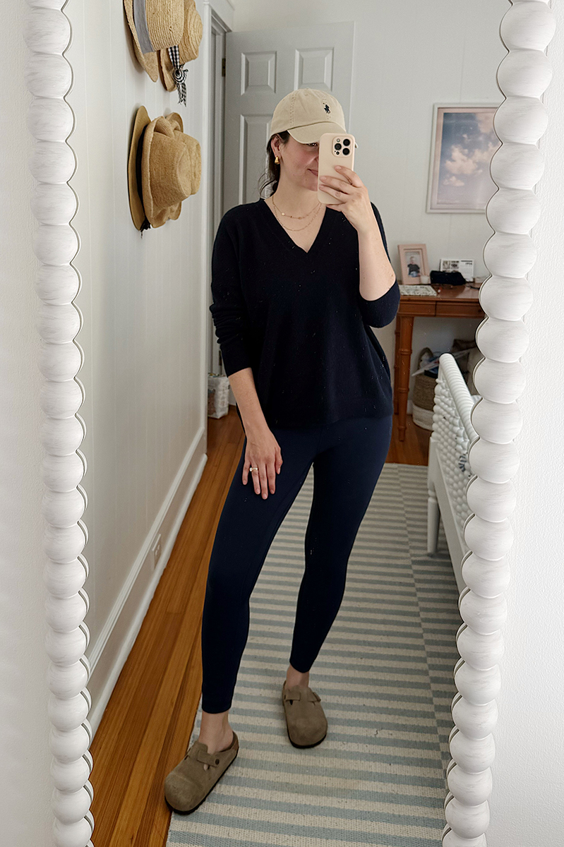 Carly in a mirror selfie wearing a navy sweater and navy leggings.