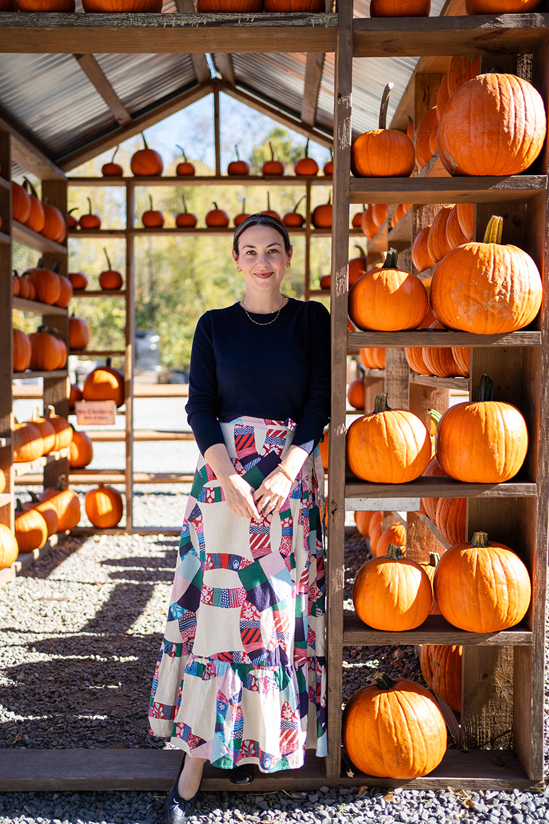 Carly wearing a patchwork skirt and navy sweater in a pumpkin house