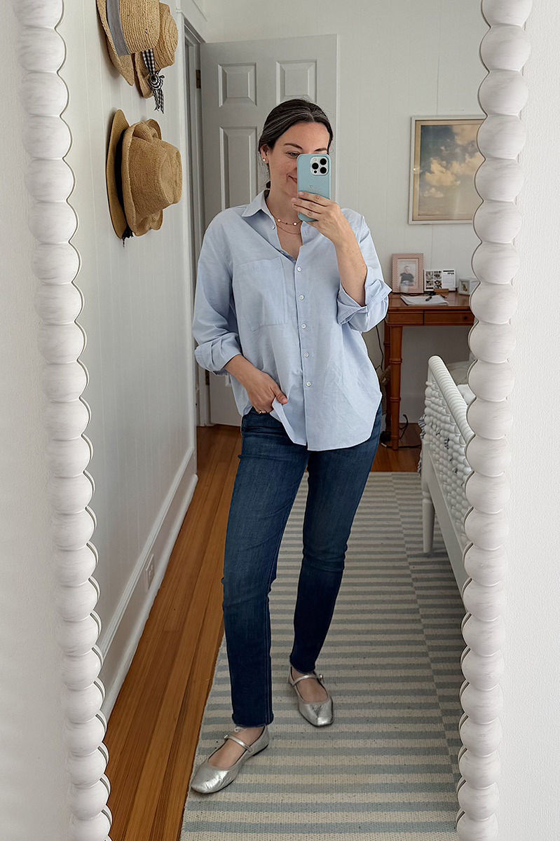 Carly Riordan taking a mirror selfie wearing an oversized button up and metallic mary janes.