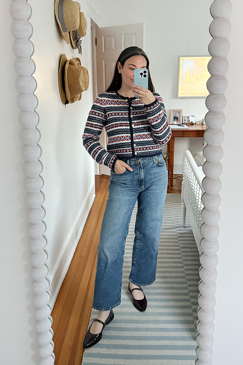 Carly Riordan taking a mirror selfie wearing a fair isle cardigan, jeans, and mary janes.