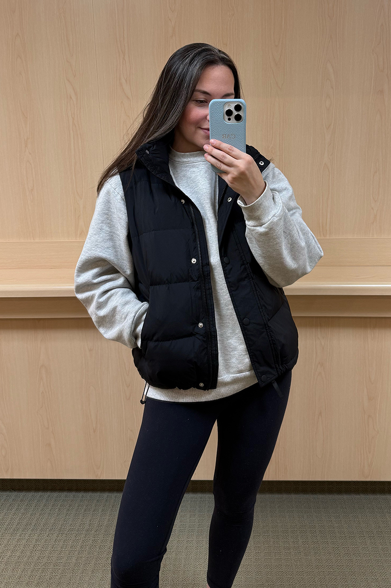 Carly Riordan taking a mirror selfie wearing a black puffer vest.