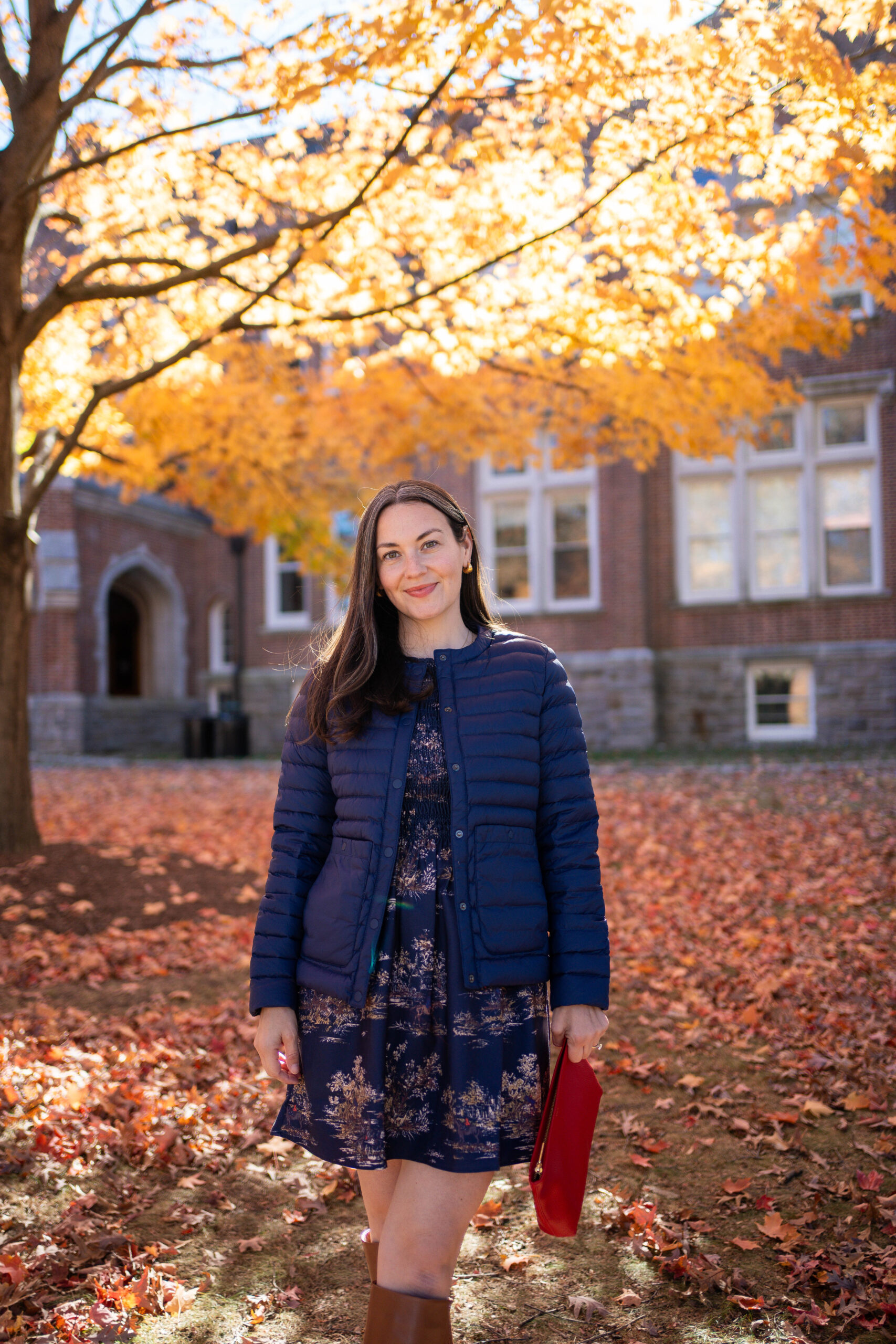 Carly Riordan wearing a Vivi nap dress with a fall toile print and tall boots and a navy puffer vest.