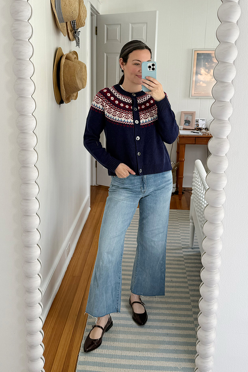 Carly Riordan taking a mirror selfie wearing a fair isle cardigan and mary janes.