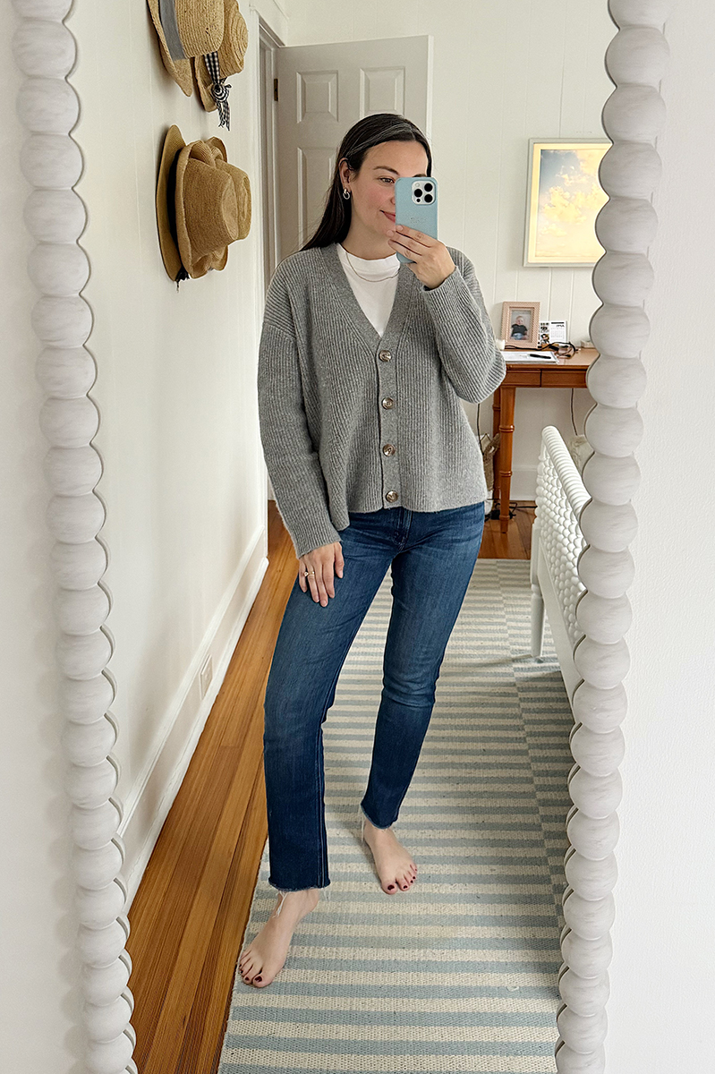 Carly Riordan taking a mirror selfie wearing a cardigan and jeans.