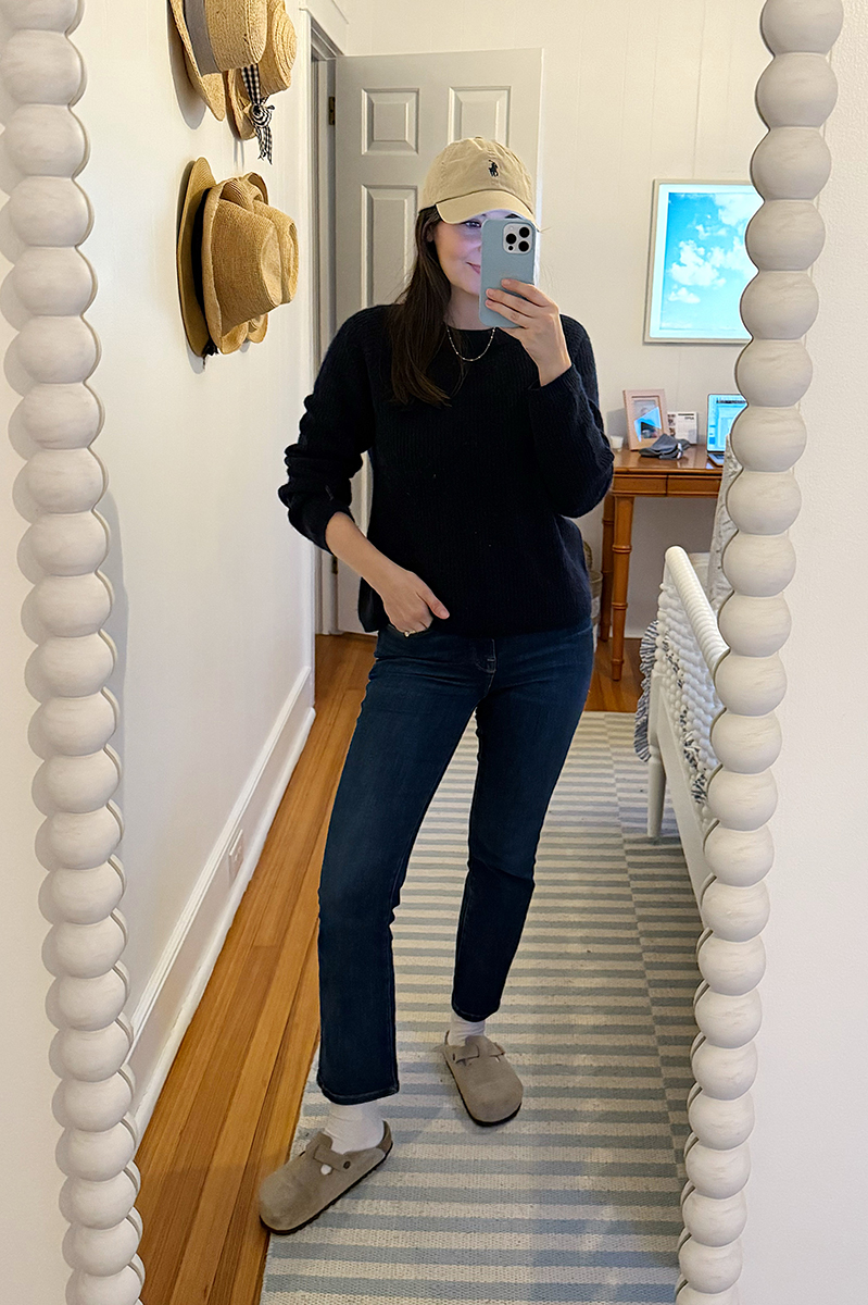 Carly Riordan taking a mirror selfie wearing a baseball cap and bsoton clogs.