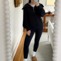 Carly Riordan taking a mirror selfie wearing leggings and a navy pullover.