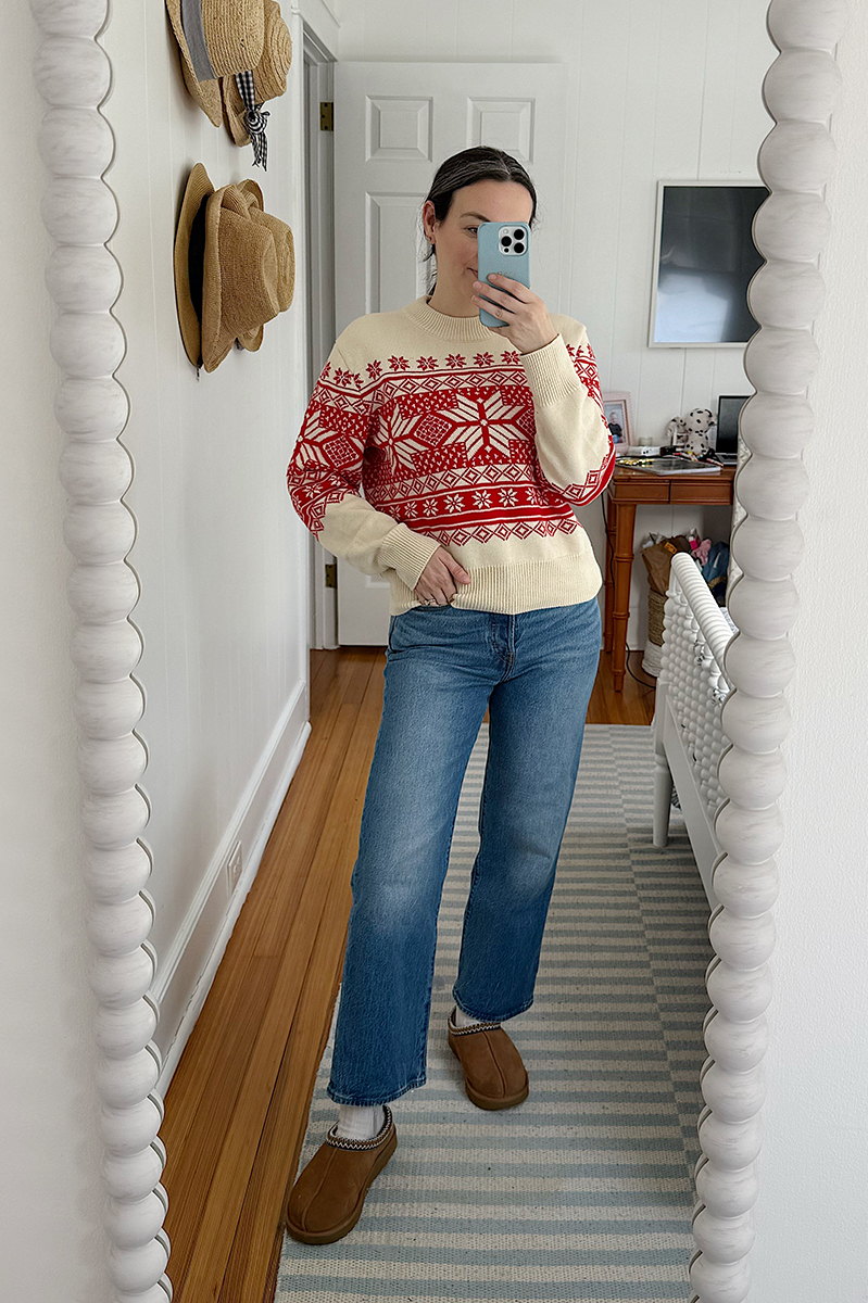 Carly Riordan taking a mirror selfie wearing a fair isle sweater, jeans, and clogs.