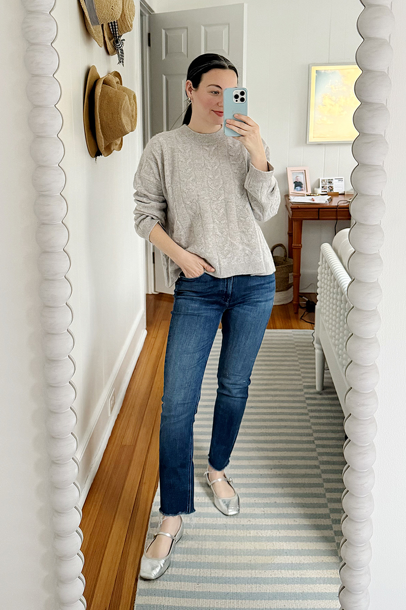 Carly Riordan wearing a grey cableknit sweater and jeans.